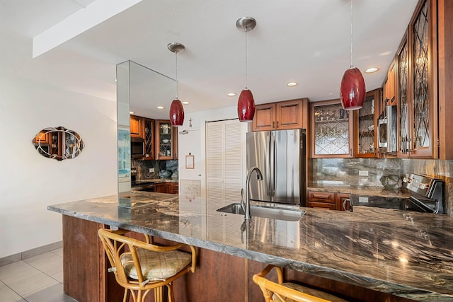 kitchen with kitchen peninsula, dark stone counters, a breakfast bar, stainless steel appliances, and sink