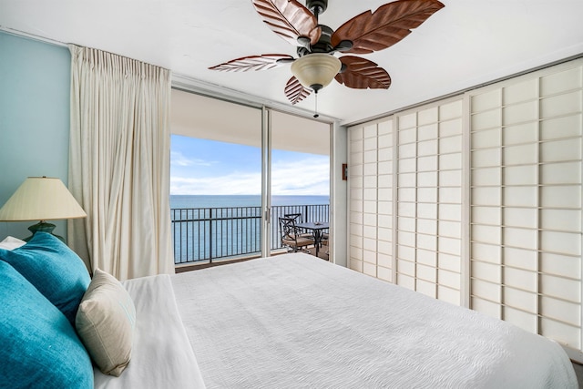 bedroom featuring access to exterior, expansive windows, a water view, and ceiling fan