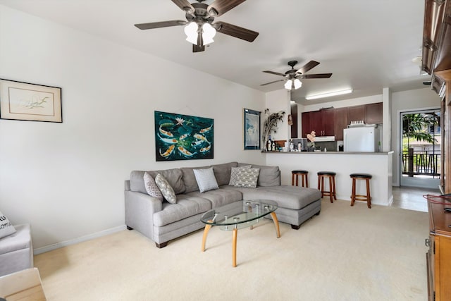 living room with baseboards, ceiling fan, and light carpet