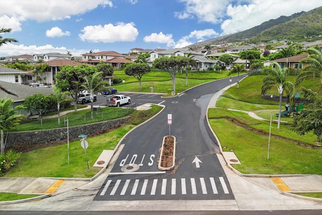 view of road featuring a residential view, a mountain view, traffic signs, and curbs