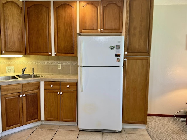 7146 Kamehameha V Hwy Unit C107, Kaunakakai, HI 96748 - kitchen with freestanding refrigerator, tile countertops, a sink, brown cabinetry, and baseboards