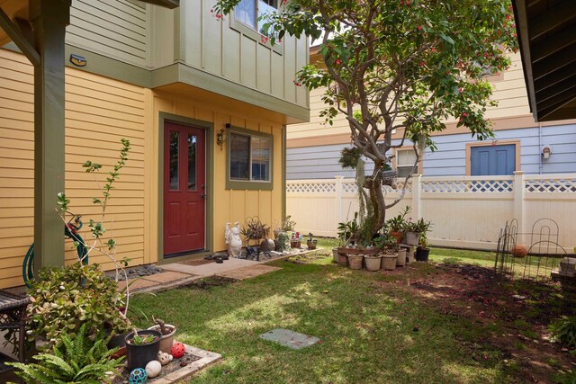 62 Meheu Cir, Kahului, HI 96732 - view of exterior entry featuring board and batten siding, fence, and a lawn