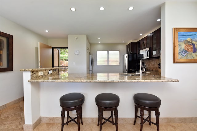 kitchen featuring light tile patterned floors, decorative backsplash, stainless steel appliances, and dark brown cabinetry