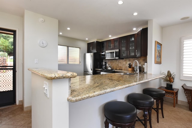 kitchen with light tile patterned floors, a healthy amount of sunlight, stainless steel appliances, and dark brown cabinetry