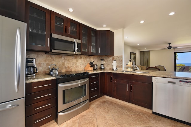 kitchen with decorative backsplash, stainless steel appliances, light stone countertops, ceiling fan, and sink