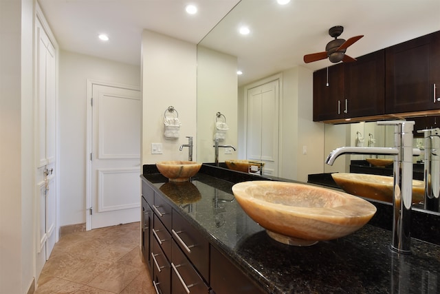 kitchen with dark stone countertops, ceiling fan, sink, light tile patterned flooring, and dark brown cabinetry