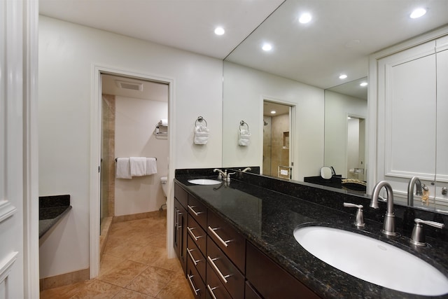 bathroom with dual bowl vanity, toilet, and tile patterned flooring