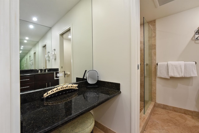 bathroom with a shower with shower door, vanity, and tile patterned floors