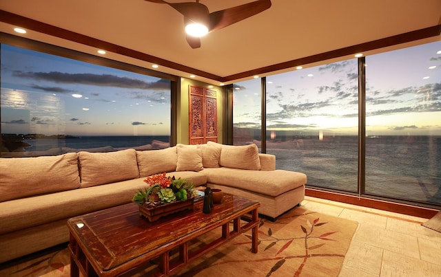 sunroom / solarium featuring ceiling fan and a water view