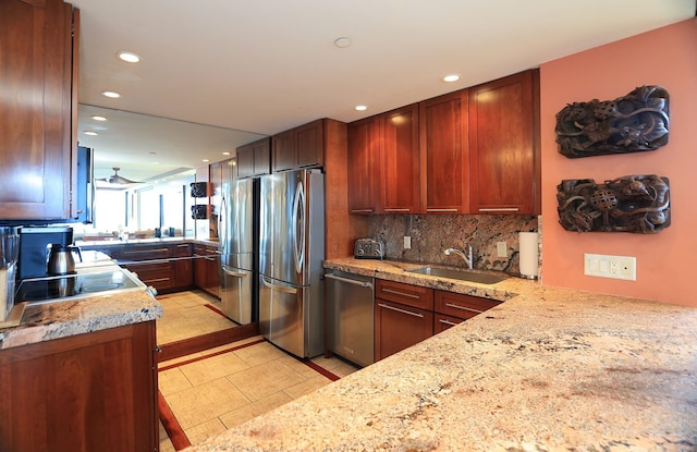 kitchen featuring sink, kitchen peninsula, decorative backsplash, light stone countertops, and appliances with stainless steel finishes