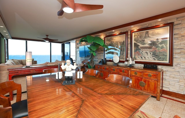 dining area with ceiling fan and a water view