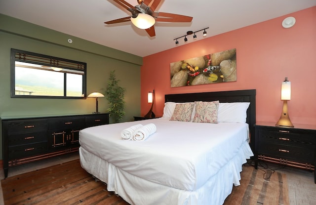 bedroom with ceiling fan, dark wood-type flooring, and track lighting