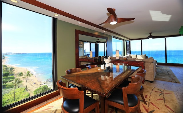 dining space with a wall of windows, ceiling fan, and a water view