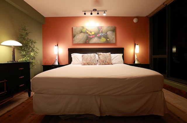 bedroom featuring rail lighting and hardwood / wood-style floors