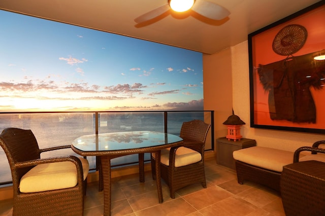 balcony at dusk with ceiling fan and a water view