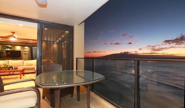 balcony at dusk featuring an outdoor living space and a water view