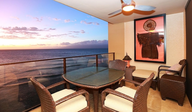 balcony at dusk with ceiling fan and a water view