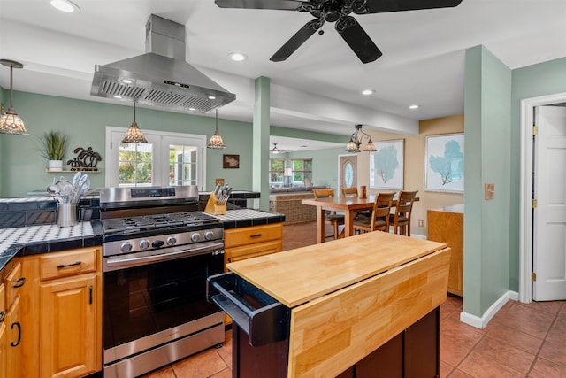 473 Kalalau Pl, Kihei, HI 96753 - kitchen featuring stainless steel range with gas cooktop, wall chimney range hood, a ceiling fan, light tile patterned floors, and tile countertops