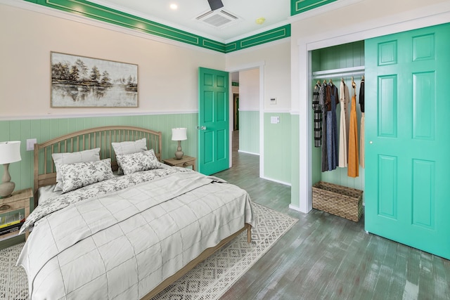 bedroom featuring dark hardwood / wood-style floors, crown molding, and a closet