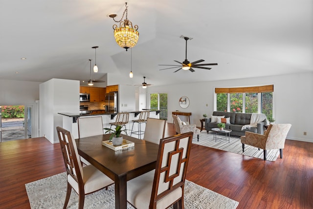 dining area with vaulted ceiling, ceiling fan with notable chandelier, and wood-type flooring