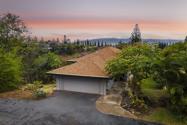 exterior space featuring a garage and roof with shingles