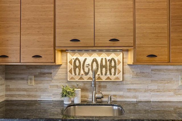 room details with dark stone counters, brown cabinetry, tasteful backsplash, and a sink