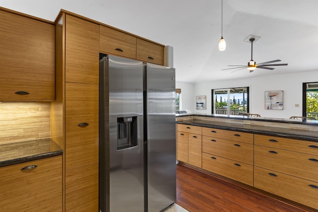 kitchen featuring brown cabinets, a healthy amount of sunlight, dark wood-style flooring, and stainless steel refrigerator with ice dispenser