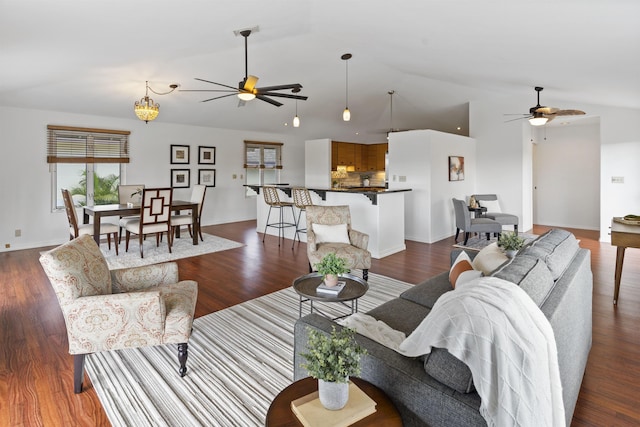 living room featuring baseboards, dark wood-type flooring, high vaulted ceiling, and ceiling fan with notable chandelier