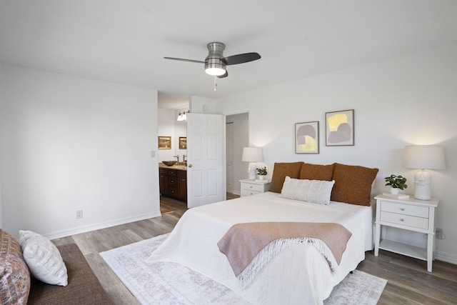 bedroom with a ceiling fan, ensuite bathroom, baseboards, and wood finished floors