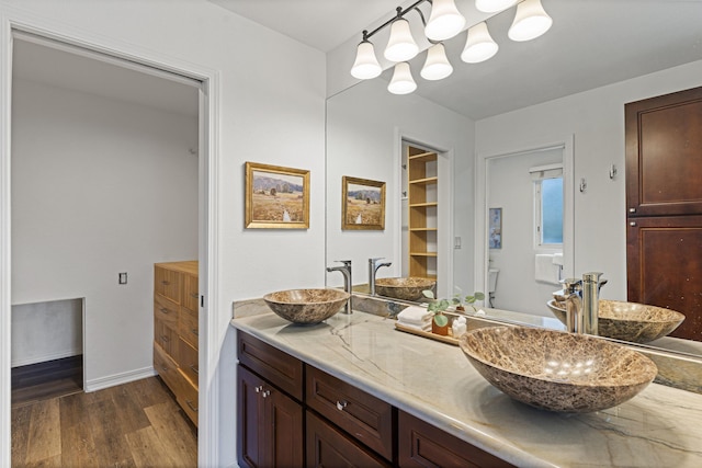 full bathroom with double vanity, wood finished floors, and a sink