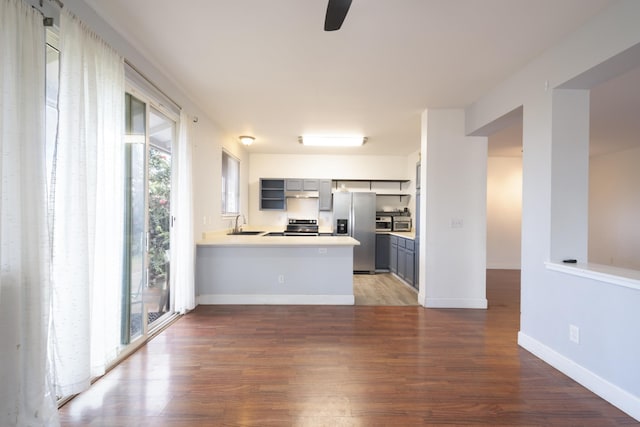 kitchen featuring gray cabinets, dark hardwood / wood-style floors, sink, kitchen peninsula, and stainless steel appliances