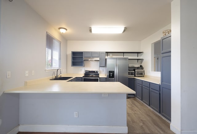 kitchen with hardwood / wood-style flooring, stainless steel appliances, kitchen peninsula, and sink