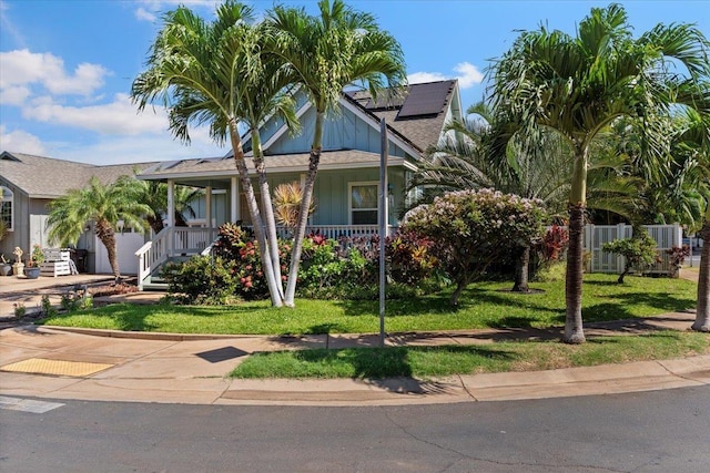 view of front of property with a front lawn, covered porch, and solar panels