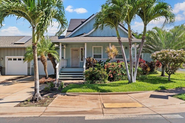 view of front facade featuring a garage, covered porch, a front yard, and solar panels