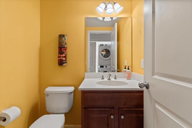 bathroom featuring vanity, stacked washing maching and dryer, and toilet