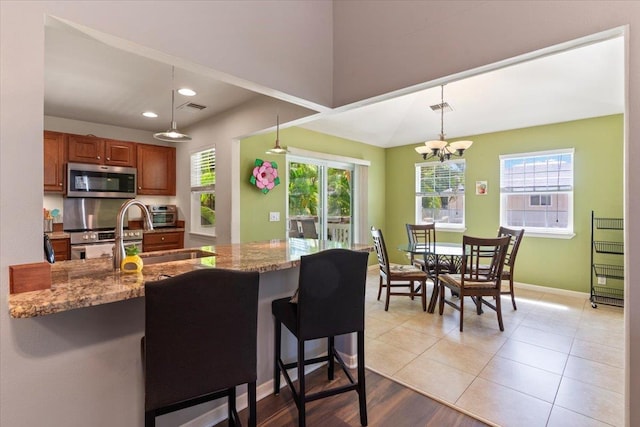 kitchen featuring a kitchen bar, sink, pendant lighting, and appliances with stainless steel finishes