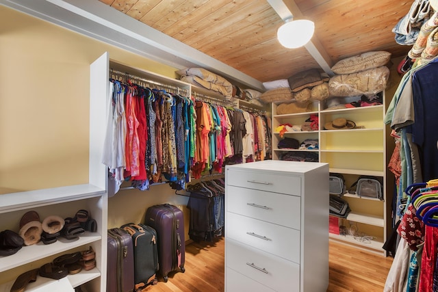 walk in closet with beamed ceiling and light wood-type flooring