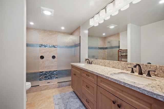 bathroom featuring double vanity, toilet, walk in shower, and a sink