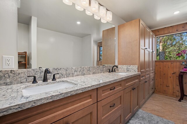 bathroom featuring a sink, wood walls, and double vanity