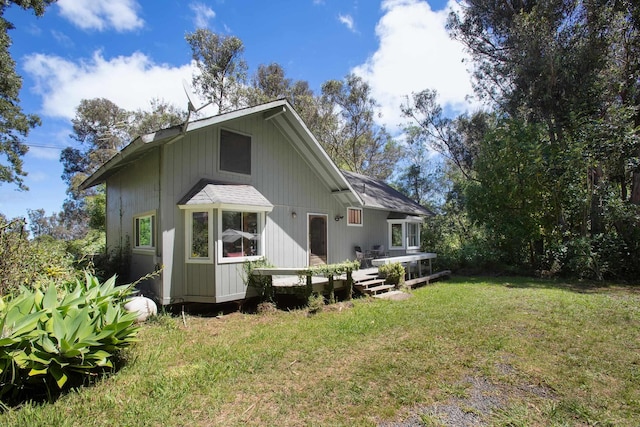 back of property featuring a wooden deck and a yard