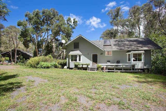 back of house featuring a lawn, a deck, and a shingled roof