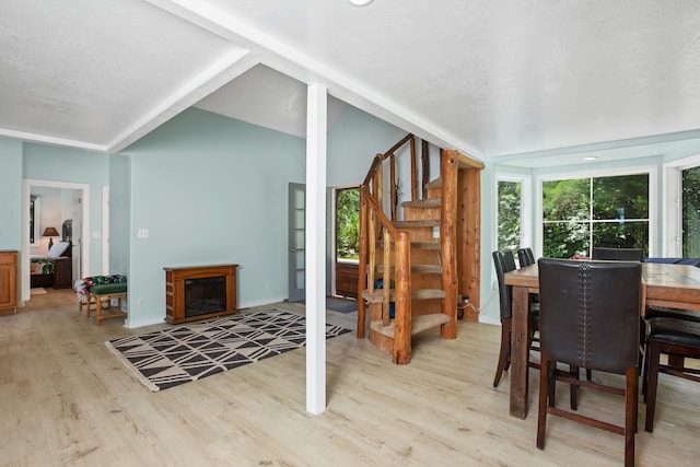 dining area with a textured ceiling, wood finished floors, stairway, baseboards, and lofted ceiling