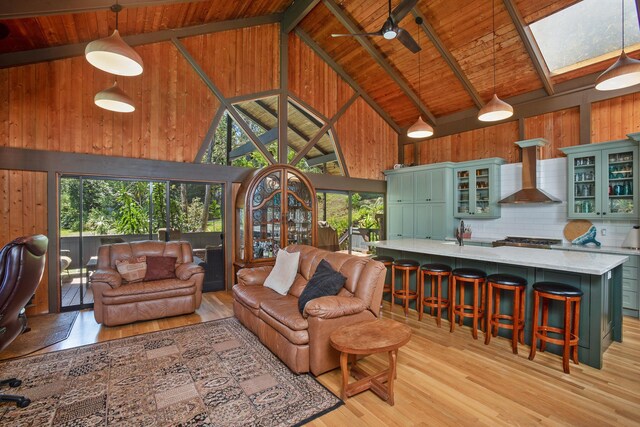 living area with light wood-type flooring, beam ceiling, high vaulted ceiling, wood walls, and wood ceiling