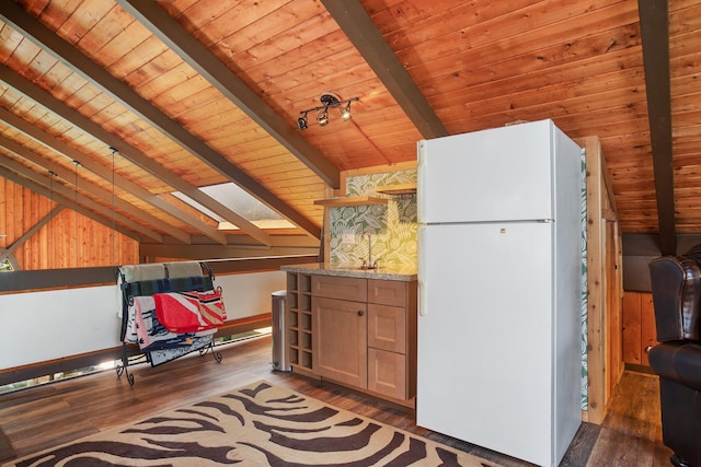 kitchen featuring light stone counters, wood finished floors, freestanding refrigerator, vaulted ceiling with skylight, and wooden ceiling