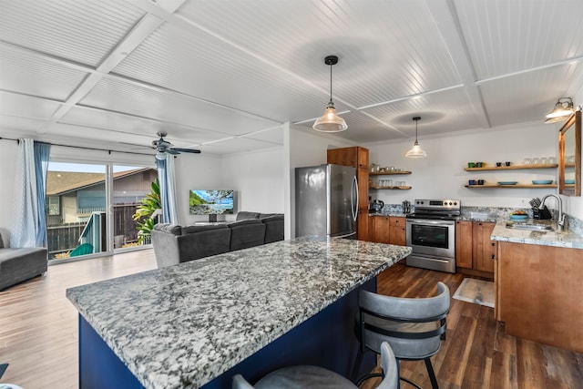 kitchen with sink, a kitchen bar, dark hardwood / wood-style flooring, hanging light fixtures, and stainless steel appliances