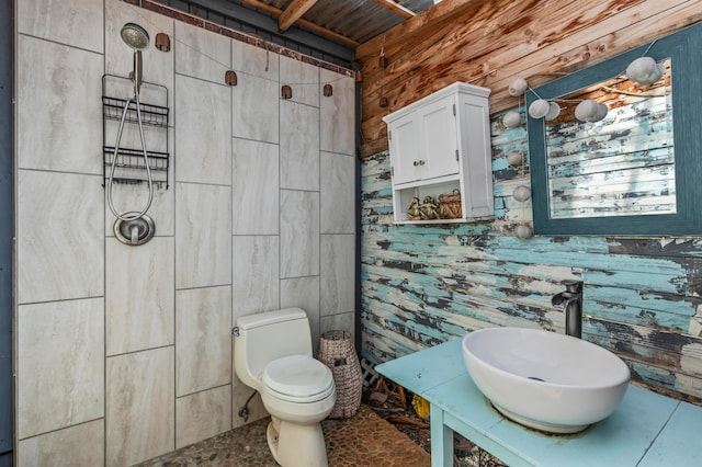 bathroom featuring sink, toilet, and wooden walls