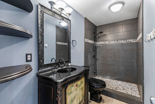 bathroom with vanity, a tile shower, toilet, and tile patterned floors