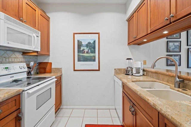 kitchen featuring sink, white appliances, light tile patterned floors, light stone counters, and decorative backsplash