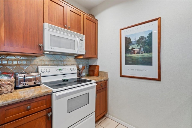 kitchen with light stone counters, backsplash, white appliances, and light tile patterned floors