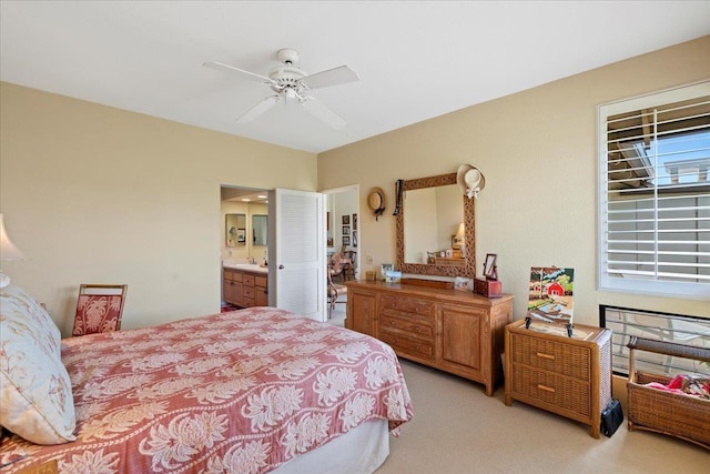 bedroom with ensuite bathroom, light carpet, and ceiling fan